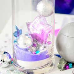 a glass vase filled with ornaments on top of a table