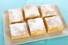 four pieces of cake on a plate with powdered sugar toppings and blue table cloth