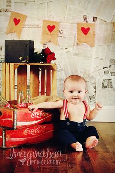 a baby sitting on the floor next to a coca - cola crate