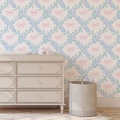 a white dresser sitting in front of a wall with pink and blue flowers on it