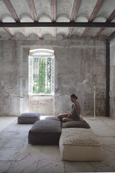 a woman sitting on top of a bed in a room with stone walls and flooring