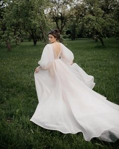 a woman in a white dress is walking through the grass