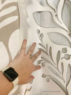 a person is using a cell phone to paint a wall with decorative stencils