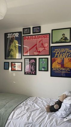 a bedroom with posters on the wall and a teddy bear laying on the bed in front of it