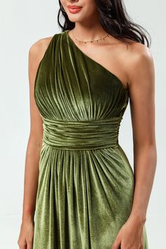 a woman wearing a green dress with one shoulder and an asymmetrical design