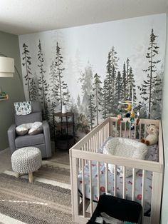 a baby's room with a crib, chair and large mural on the wall