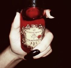 a woman's hand holding a bottle of vampire wine