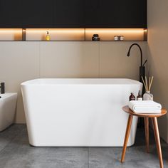 a white bath tub sitting next to a wooden stool