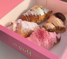 a pink box filled with assorted pastries on top of a grass covered field