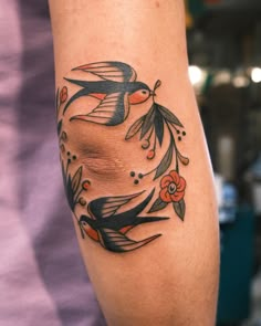 a woman's arm with a bird and flower tattoo design on the left forearm