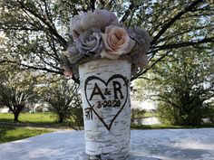 a vase filled with flowers sitting on top of a table next to a tree trunk