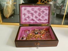 an open wooden box with jewelry in it on a table next to a framed photo