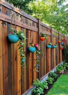 a wooden fence with hanging flower pots on it