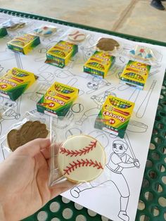 a person holding a cookie in front of a table with baseball cookies and candy on it