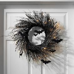 a halloween wreath with bats hanging from it's side and lights on the front door