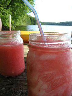 two mason jars filled with pink drink sitting next to each other on top of a wooden table