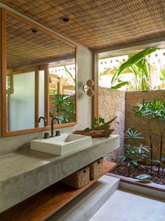 a bathroom with two sinks and plants in the window sill, along with an outdoor shower