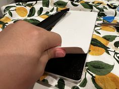 a person is holding a pen and cutting something out of a box on a table