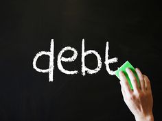 a hand writing the word debt on a blackboard