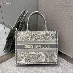 SHOP MORE LUXURY PRODUCTS HERE Description Christian Dior Medium Dior Book Tote Bag By Maria Grazia Chiuri Grey For Women 14in/36cm CD M1296ZTDT_M932 Dimensions: 36 x 27.5 x 16.5 cm / 14 x 11 x 6.5 inches Introduced by Maria Grazia Chiuri, Creative Director of Christian Dior, the Dior Book Tote has become a staple of the Dior aesthetic. Designed to hold all the daily essentials, the style is fully embroidered with a gray Toile de Jouy motif. Adorned with the ‘CHRISTIAN DIOR PARIS’ si Christian Dior Tote Bag, Christian Dior Tote, Dior Tote Bag, Christian Dior Handbags, Dior Aesthetic, Dior Book, Christian Dior Paris, Louis Vuitton Shirt, Chanel Shirt