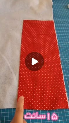 someone is making a red and white polka dot fabric on a piece of blue paper