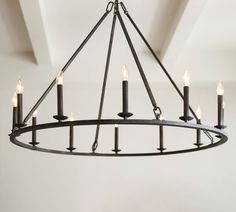 a circular chandelier with candles hanging from it's center ring in an empty room