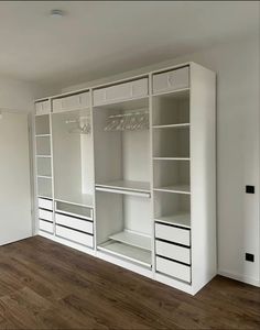 an empty room with some white shelves and drawers in it, including two closets