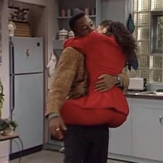 a man and woman hug in the kitchen