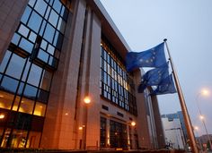 the european flag is flying in front of a large building with windows and street lights