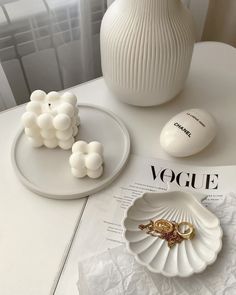 a white vase sitting on top of a table next to some rings and an egg