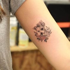 a small tattoo on the arm of a woman with a dog and flowers in it