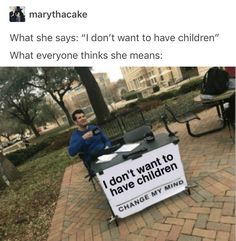 a man sitting at a table with a sign on it that says, what she says don't want to have children change my mind