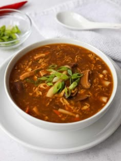 a white plate topped with a bowl of soup