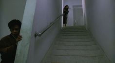 two people are walking down the stairs in an empty building with white walls and concrete floors