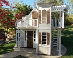 a white house with wooden shutters on the front and second story, surrounded by green grass