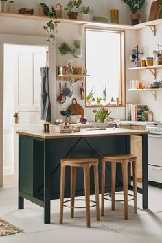 two stools sit in front of an island with potted plants on the shelves