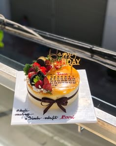 a birthday cake with fruit and writing on it