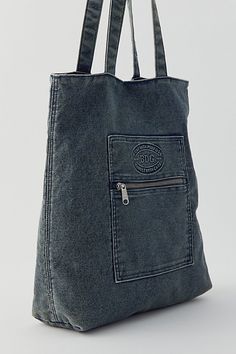 a denim bag with zippers on the front and side, hanging from a hook