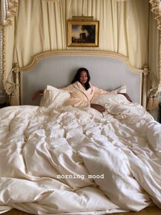 a woman laying in bed with white sheets