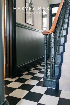 a black and white checkered floor next to a staircase with wooden handrails