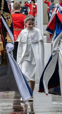 two girls dressed in white and blue are walking down the street with other people behind them