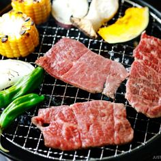 steaks and corn on the cob are cooking on an outdoor bbq grill