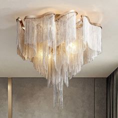 a chandelier hanging from the ceiling in a room with grey walls and curtains