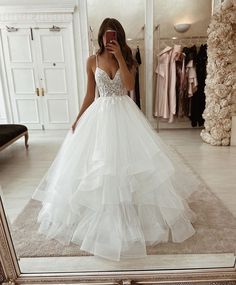 a woman taking a selfie in front of a mirror wearing a white wedding dress