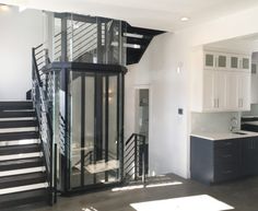 an empty kitchen and staircase in a house with white walls, black flooring and cabinets