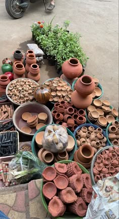 many clay pots and bowls on display in front of a motor scooter parked next to each other