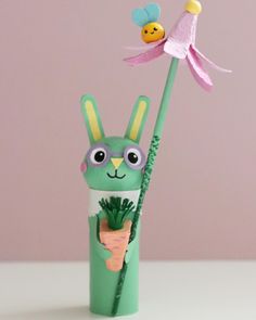 a paper mache bunny holding a carrot and flower