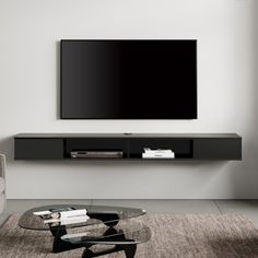 a living room with a large flat screen tv mounted on the wall above a glass coffee table