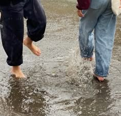 three people standing in the water with their feet up and one person holding an umbrella