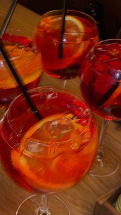 three glasses filled with different types of drinks on top of a wooden table next to plates and utensils